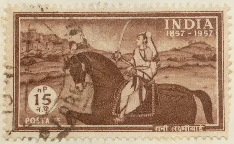 Frimärke ur Gösta Bodmans filatelistiska motivsamling, påbörjad 1950.
Frimärke från Indien, 1957. Motiv av Indiska furstinnan: "Rani Laxmibai" av Jhansi som rytterska med svärd. -100-årsminne av Indiens frihetskamp eller s.k. "Indian mutiny i 1857" ochså kallat sepoyrevolten mot brittiskt herravälde. (sepoys= indiska soldater i engelska regementen) 1857-1957.