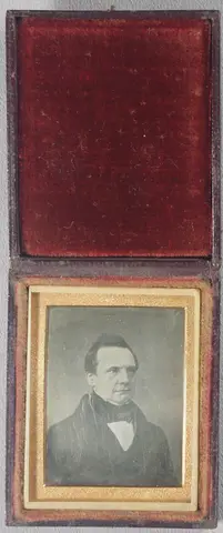 Head and shoulders portrait of Charles Babbage, the mathematician, philosopher, inventor and mechanical engineer. He is best remembered for originating the concept of a programmable computer, the Difference Engine. He is clean-shaven with dark hair, wears a dark jacket, white shirt and dark cravat. The case opens along the shorter edge.