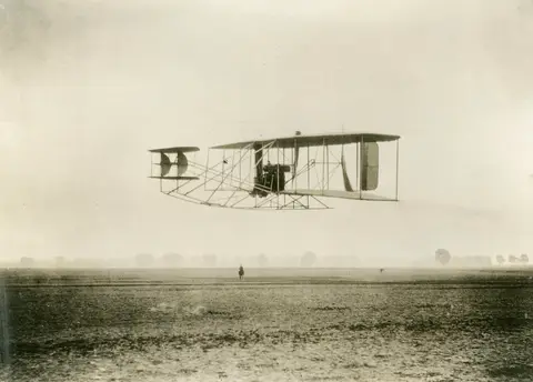 Wilbur Wright flyger Model A Flyer, Tempelhoferfältet, Berlin, sommaren 1909, mellan 30 augusti och 18 september.
Motor 26kW. Model Flyer A såg dagens ljus 1906, och var en utveckling av Flyer III från 1905. Model A var den försa modellen som avsågs för kokmmersiell produktion.